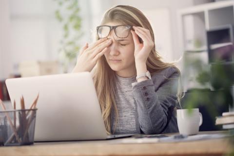 Una mujer se frota los ojos ante su ordenador portátil